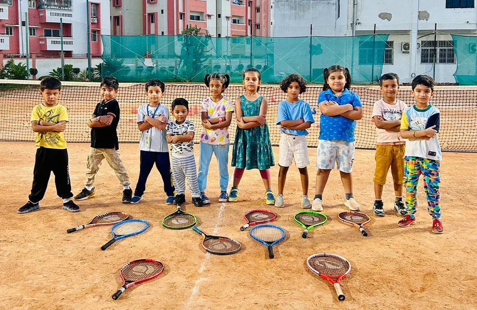 Young mini tennis players standing behind racquets laid out on a clay court